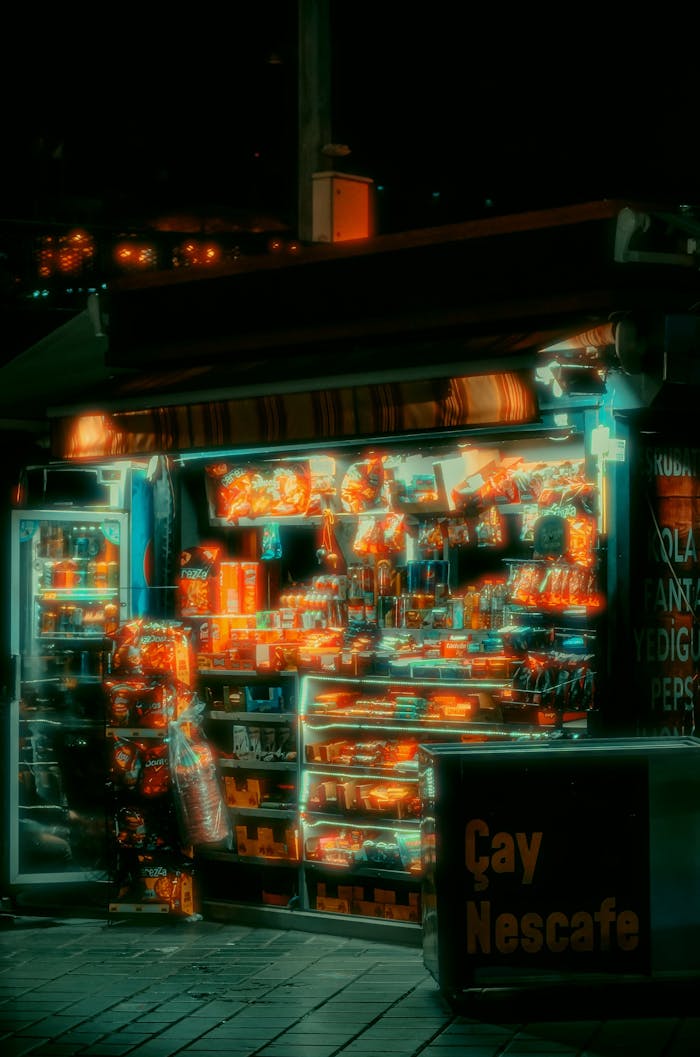 A vibrant newsstand in Istanbul illuminated at night, displaying snacks and drinks under neon lights.