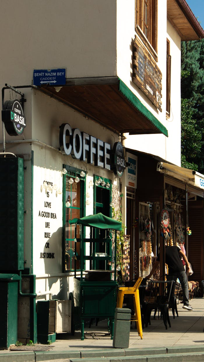 Quaint coffee shop exterior on a sunny street corner with people enjoying afternoon beverages.